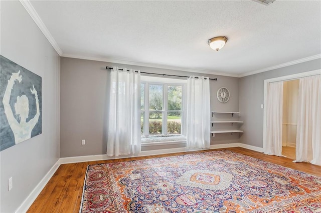 unfurnished room featuring a textured ceiling, wood-type flooring, and ornamental molding