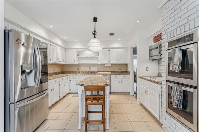 kitchen featuring a center island, light stone countertops, stainless steel appliances, and white cabinetry