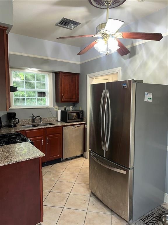 kitchen featuring ceiling fan, light stone counters, sink, light tile patterned flooring, and stainless steel appliances