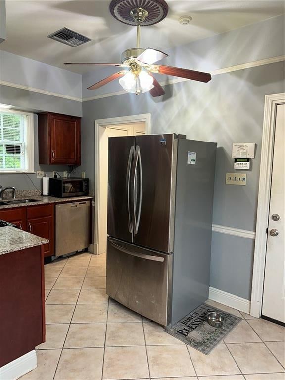 kitchen featuring stainless steel appliances, sink, light stone countertops, ceiling fan, and light tile patterned flooring