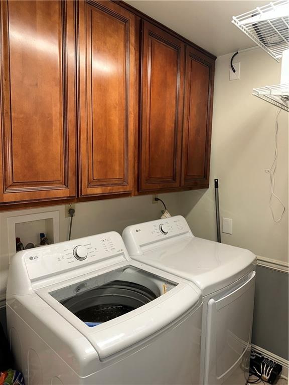 laundry room featuring washing machine and dryer and cabinets