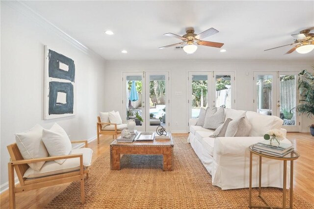 living room featuring french doors, light hardwood / wood-style floors, ceiling fan, and crown molding