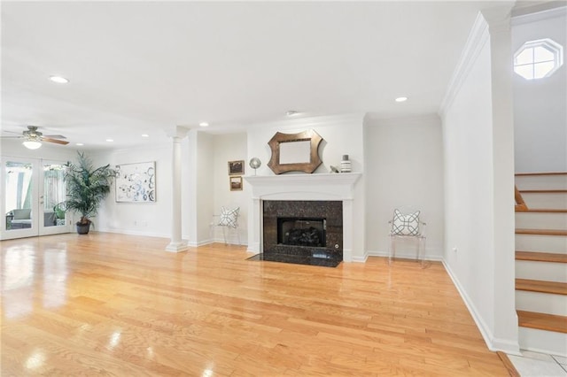 unfurnished living room featuring ceiling fan, french doors, crown molding, light hardwood / wood-style floors, and a fireplace