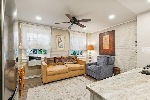 living room with ceiling fan, hardwood / wood-style flooring, and brick wall