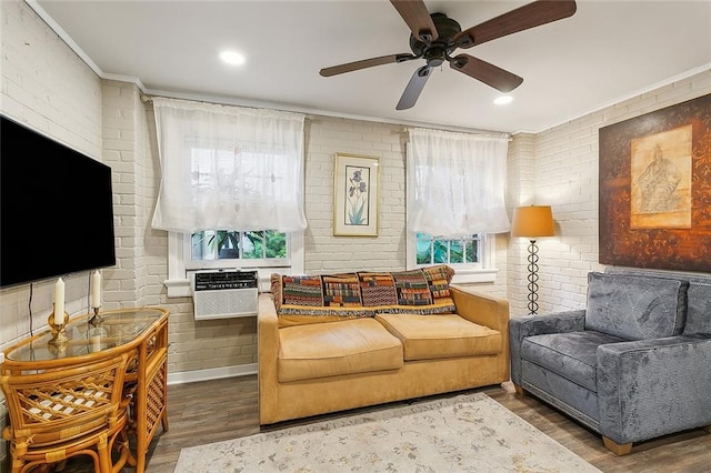 living room with ceiling fan, wood-type flooring, brick wall, and ornamental molding