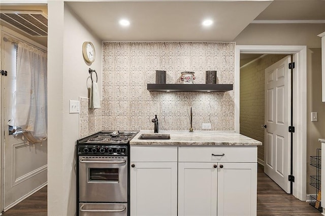 kitchen featuring gas stove, dark wood-type flooring, decorative backsplash, and white cabinets