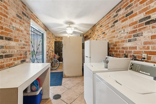 washroom featuring ceiling fan, light tile patterned floors, brick wall, and washing machine and dryer