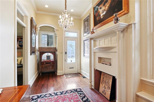 foyer featuring ornate columns, ornamental molding, dark hardwood / wood-style flooring, and a chandelier