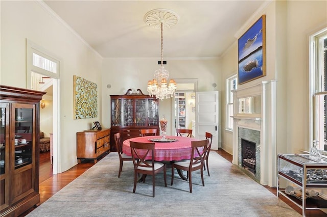 dining room featuring hardwood / wood-style floors, an inviting chandelier, ornamental molding, and a fireplace