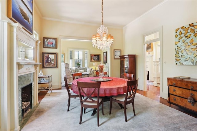 dining space featuring hardwood / wood-style floors, an inviting chandelier, ornamental molding, and a fireplace