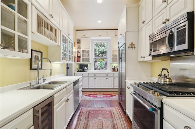 kitchen with sink, wine cooler, dark wood-type flooring, high quality appliances, and white cabinetry