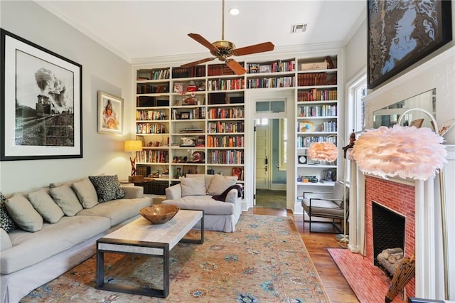 sitting room with crown molding, hardwood / wood-style floors, built in features, and a brick fireplace