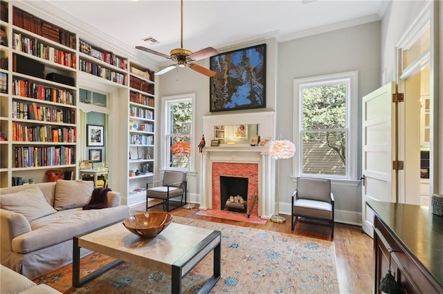 sitting room with hardwood / wood-style flooring, crown molding, a healthy amount of sunlight, and a fireplace