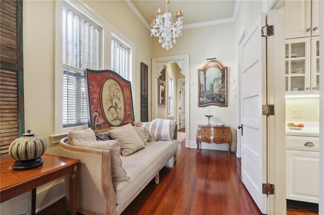 sitting room with crown molding, dark wood-type flooring, and a notable chandelier