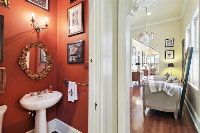 bathroom featuring a notable chandelier, wood-type flooring, and ornamental molding