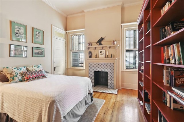 bedroom with a fireplace, light hardwood / wood-style floors, and ornamental molding