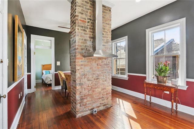 interior space with decorative columns, brick wall, and dark hardwood / wood-style flooring