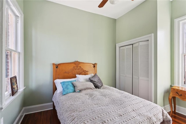 bedroom featuring ceiling fan, dark hardwood / wood-style floors, a closet, and multiple windows