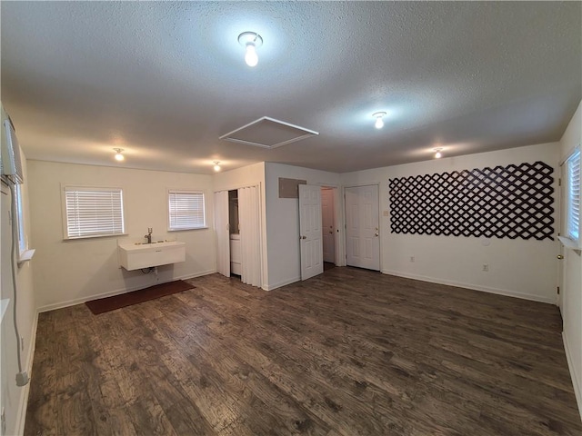 interior space with a sink, a textured ceiling, baseboards, and dark wood-style flooring