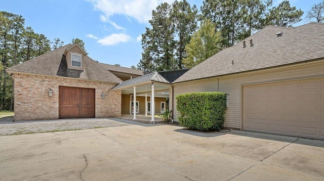 view of front of home featuring driveway, roof with shingles, and brick siding