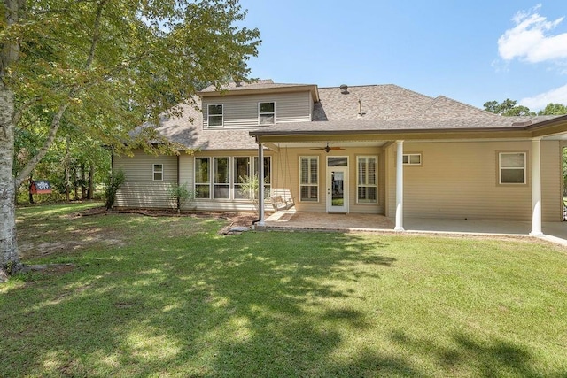 rear view of property with a patio, roof with shingles, a lawn, and a ceiling fan