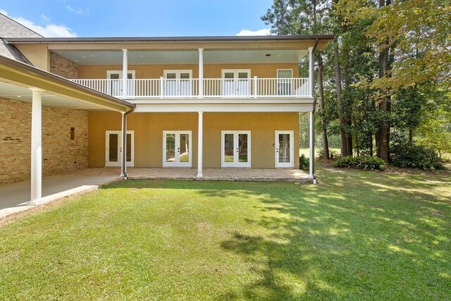 back of house featuring a balcony, french doors, a patio area, and a yard