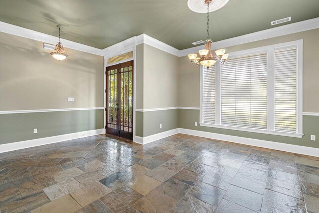 empty room with a wealth of natural light, an inviting chandelier, crown molding, and dark tile patterned floors