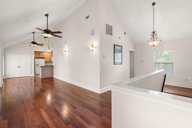 hallway with high vaulted ceiling and hardwood / wood-style floors