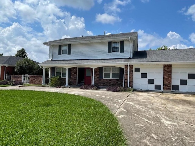 traditional home featuring a garage, brick siding, concrete driveway, and a front yard