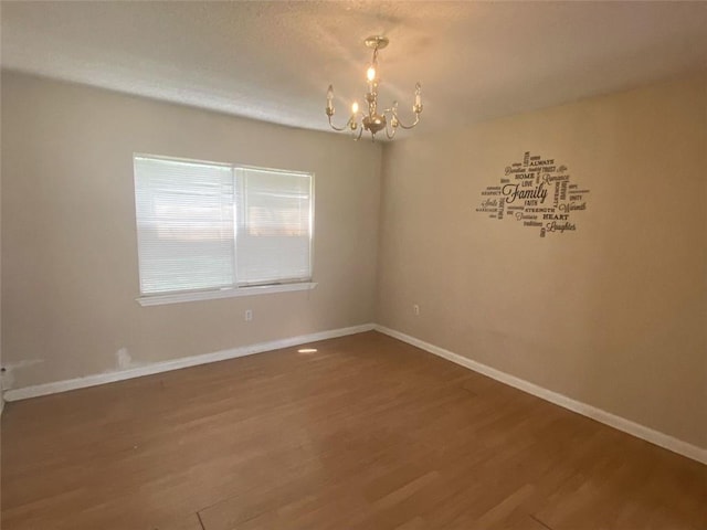 spare room with wood-type flooring and a notable chandelier