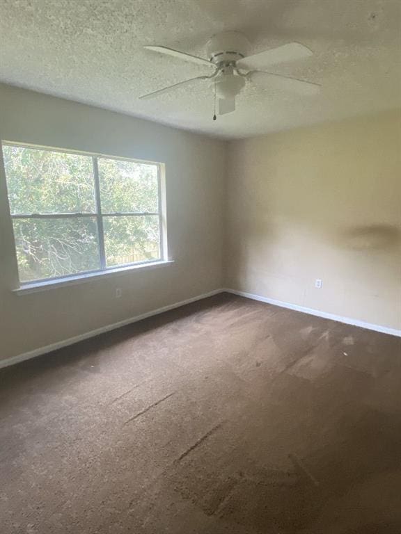 carpeted empty room featuring ceiling fan and a textured ceiling