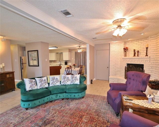 living room featuring light tile patterned floors, ceiling fan, a brick fireplace, and a textured ceiling