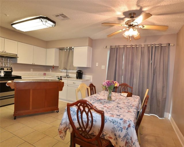 interior space with light tile patterned floors, sink, stainless steel range with electric cooktop, and white cabinetry