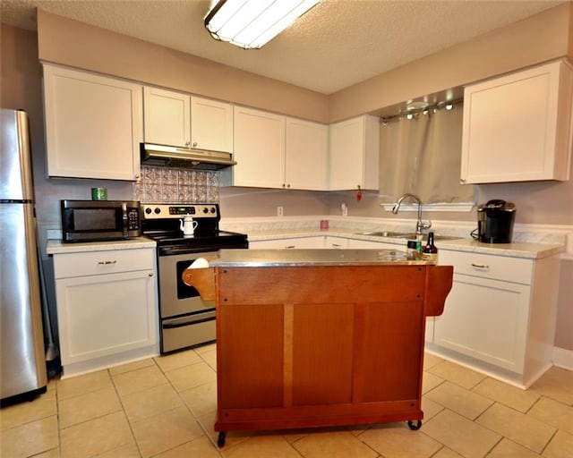 kitchen with white cabinets, appliances with stainless steel finishes, light tile patterned flooring, and a center island