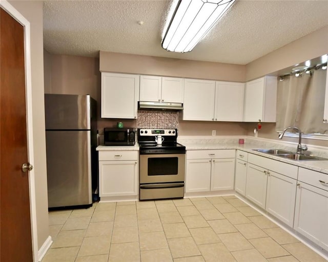 kitchen with light tile patterned flooring, appliances with stainless steel finishes, sink, and a textured ceiling