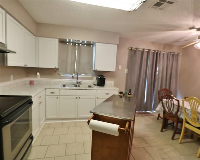 kitchen featuring sink, light tile patterned floors, white cabinetry, range, and ceiling fan