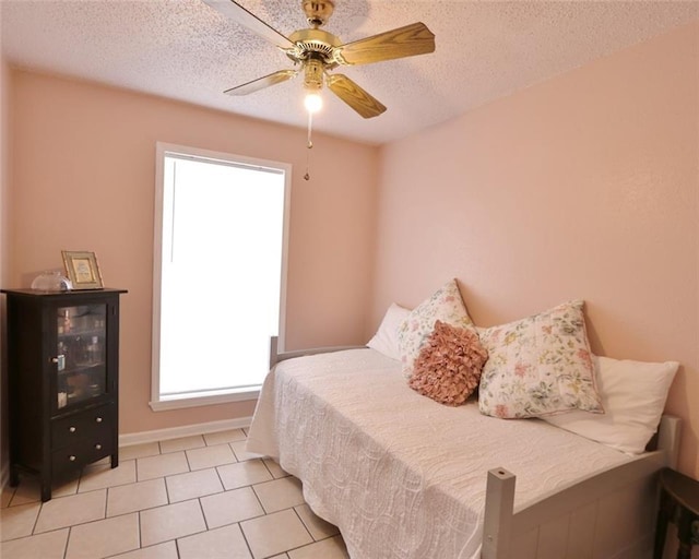 bedroom featuring ceiling fan, a textured ceiling, and light tile patterned floors