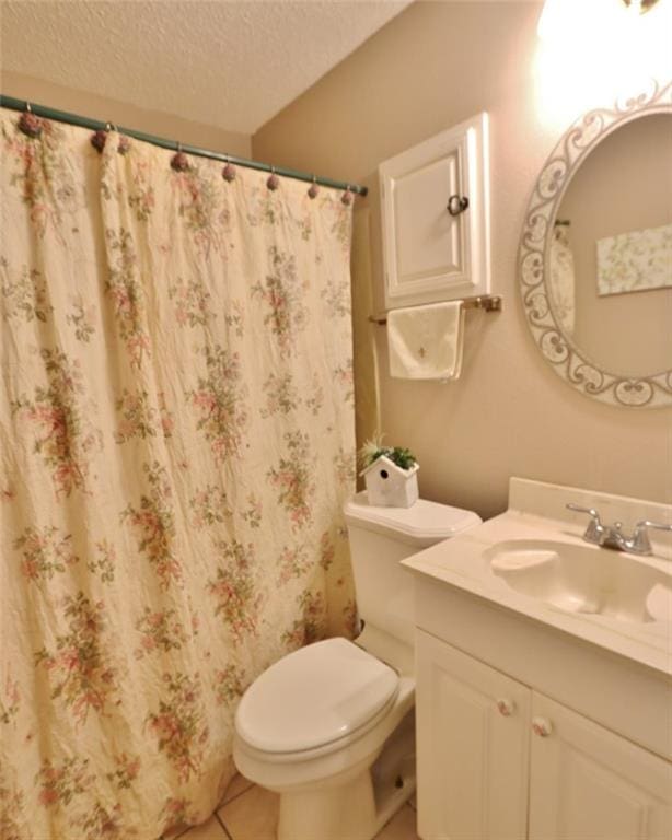 bathroom with tile patterned floors, a textured ceiling, vanity, toilet, and walk in shower