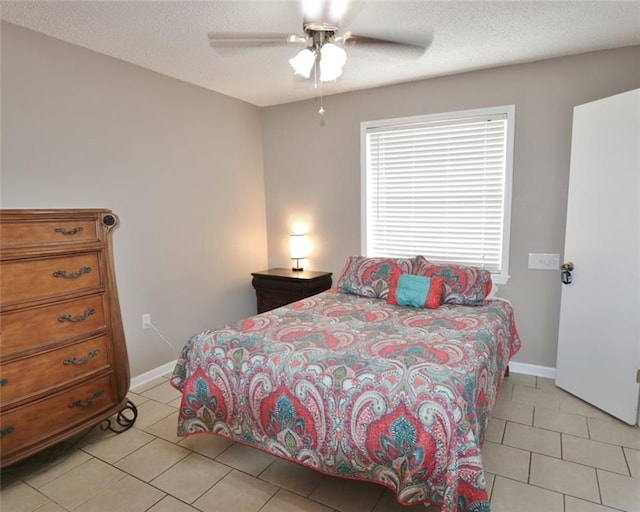 bedroom with ceiling fan, light tile patterned flooring, and a textured ceiling