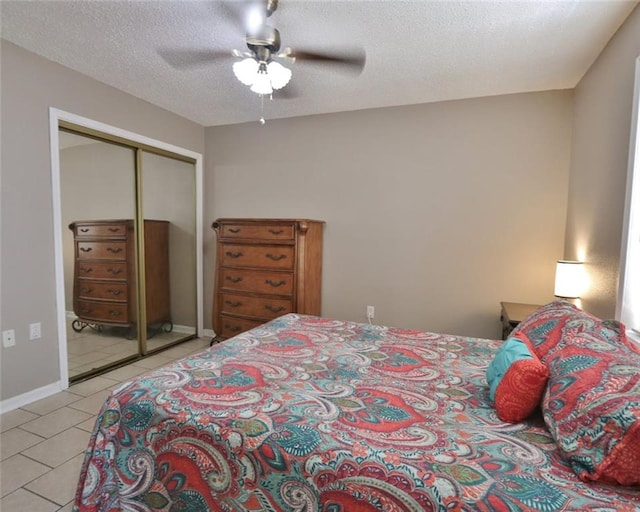 tiled bedroom with ceiling fan, a closet, and a textured ceiling