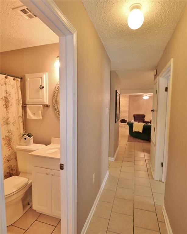 hall featuring a textured ceiling and light tile patterned floors