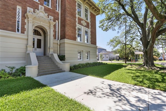 entrance to property with brick siding and a lawn