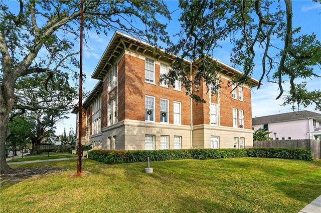 view of home's exterior featuring brick siding, a yard, and fence