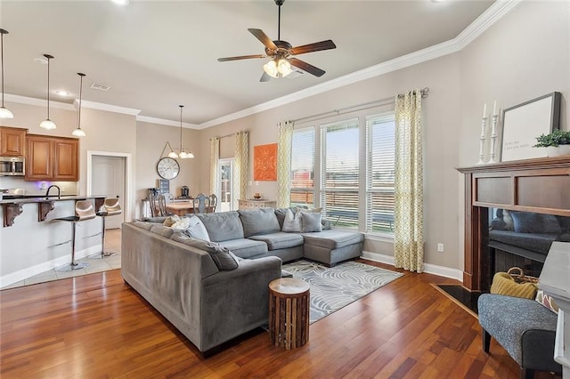 living room with crown molding, ceiling fan with notable chandelier, and hardwood / wood-style flooring