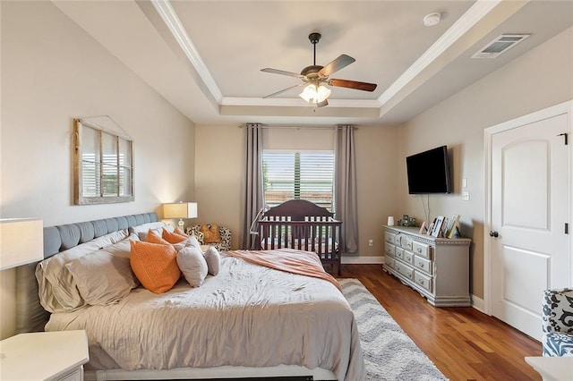 bedroom with a tray ceiling, ceiling fan, and dark hardwood / wood-style flooring