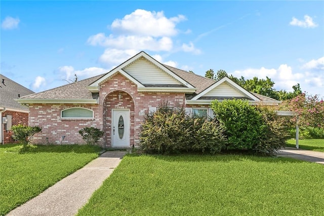 view of front of property featuring brick siding, a front lawn, and roof with shingles