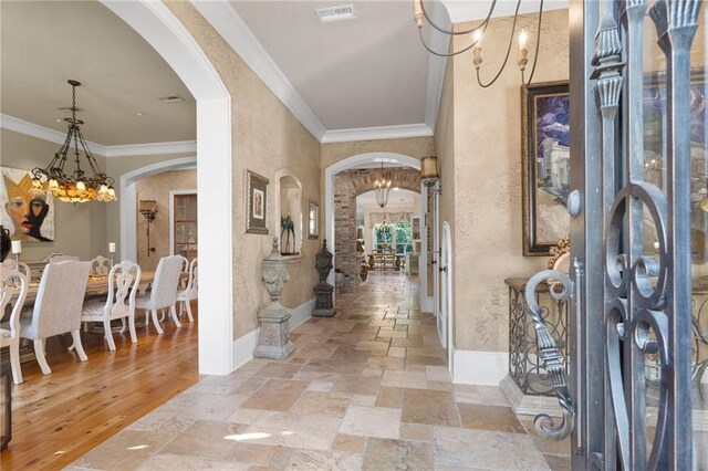 foyer with a chandelier, ornamental molding, and light wood-type flooring