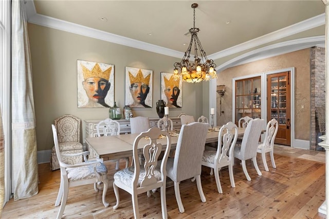 dining room with baseboards, ornamental molding, light wood-type flooring, and a notable chandelier