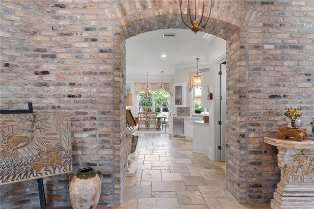 hallway featuring light tile patterned flooring and brick wall