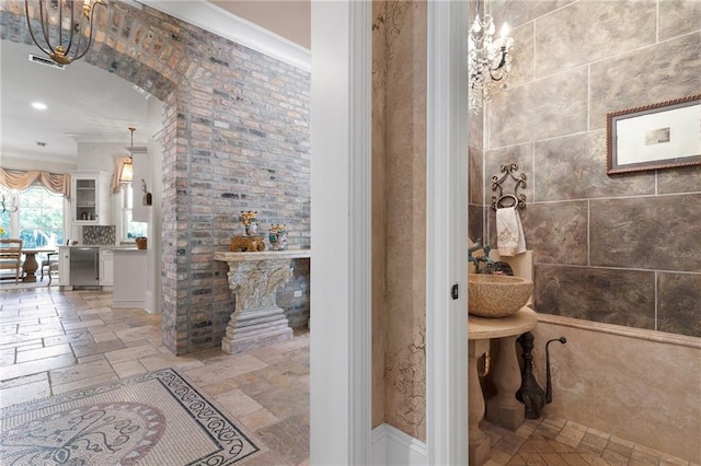 bathroom featuring stone tile floors, visible vents, and tile walls